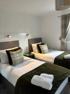 a hotel room with two beds with towels on them at Tay Villa in Inverness