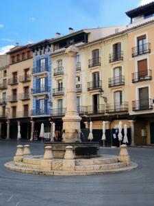 a fountain in front of a building with umbrellas at Mirador la Jardinera- céntrico con parking privado GRATIS in Teruel
