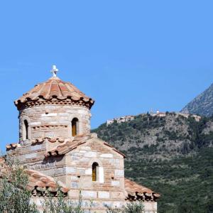 an old stone church with a mountain in the background at Tzokeika Traditional Settlement in Riglia