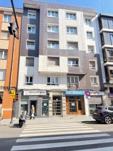 a building on the corner of a street with a person crossing the street at Soleado 2 - A 8 min a pie de la playa San Lorenzo in Gijón
