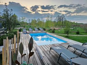 a swimming pool on a wooden deck with lounge chairs at Vaitų Riešutynė - Small shipping container house in Antanava