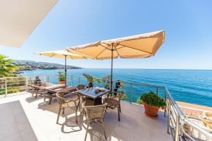 多布拉沃达Vila Dora的一个带桌子和遮阳伞的庭院,俯瞰着大海