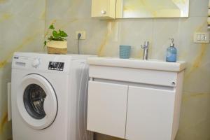 a bathroom with a washing machine and a sink at Ana's House in Orikum