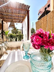 a table with two plates and a vase with pink flowers at Tanger Beach - house in Tangier