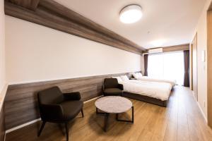 a bedroom with a bed and two chairs and a table at LIVEIL Hakataekimae in Fukuoka