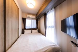 a small bedroom with a bed and a tv at LIVEIL Hakataekimae in Fukuoka