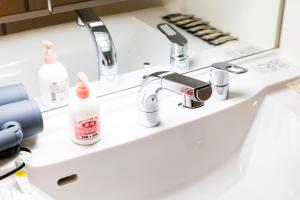 a bathroom sink with two faucets and a mirror at LIVEIL Hakataekimae in Fukuoka +28 photos