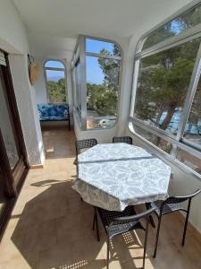 a table and chairs in a room with windows at Apartamento La Caleta in Les tres Cales
