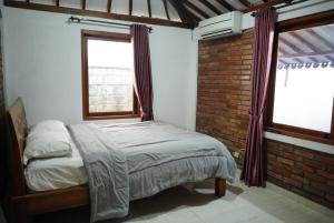a bedroom with a bed and a brick wall at Joglo Turen Villa in Ngaglik