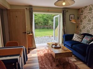 a living room with a blue couch and a table at The Drey by Blake view holidays, a peaceful boutique retreat, 3 miles from Ennerdale- small twin or king bed available in Arlecdon