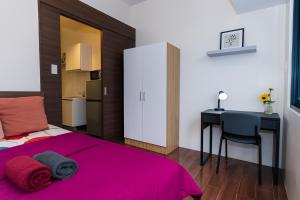 a bedroom with a pink bed and a desk at Suite Life Makati Vibes Views Relaxation 3870 in Manila