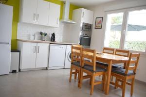 a kitchen with white cabinets and a wooden table and chairs at Maison tout confort 6 personnes à 300m de la plage - Clim & Wifi in Mimizan-Plage