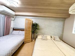 a bedroom with two beds and a potted plant at d402涉谷区域 乘电车4分钟到达新宿 巴士直达涉谷步行到西新宿五丁目8分钟 max6 in Tokyo +24 photos