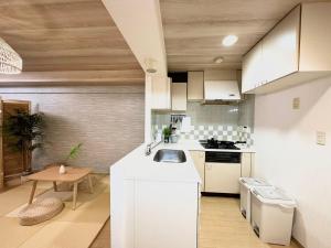 a kitchen with white cabinets and a sink and a table at d402涉谷区域 乘电车4分钟到达新宿 巴士直达涉谷步行到西新宿五丁目8分钟 max6 in Tokyo