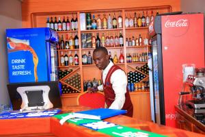 Ein Mann, der an einem Tresen in einer Bar steht. in der Unterkunft Hotel Next in Masaka