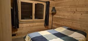 Schlafzimmer mit einem Bett, einem Fenster und einer Lampe in der Unterkunft Chalet au calme in La Bresse
