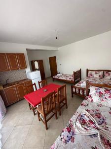 a room with three beds and a red table and chairs at Hotel Armela in Velipojë +9 photos
