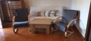 Una sala de estar con un sofá y dos sillas y una mesa. en Casa Eden, en Ploca