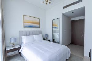 a white bedroom with a large white bed and a door at 3BR Apartment with City and Beach Views at Address Residences Marassi in Muharraq +12 photos
