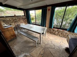 a table and bench in a room with windows at Charmante retraite champêtre in Bagnols-en-Forêt