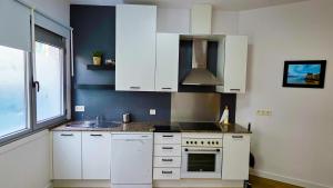 a kitchen with white cabinets and a sink at Rías Baixas Playa Vilariño, Ria de Aldan in Aldán
