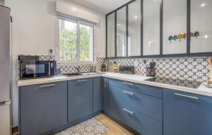 a kitchen with blue cabinets and a microwave at 3 Bedroom Cozy Home In La Tremblade in La Tremblade +20 photos