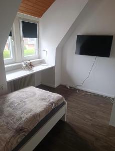 a bedroom with a bed and a flat screen tv at Ferienwohnung Herzberg in Loxstedt