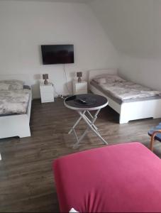 a room with two beds and a table and a tv at Ferienwohnung Herzberg in Loxstedt