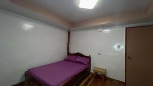 a small bedroom with a purple bed in it at Aviniel Cottage in Puerto Galera