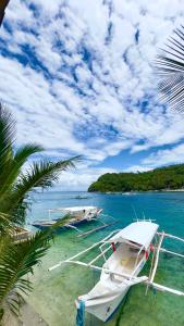 a white boat in the water next to a beach at Aviniel Cottage in Puerto Galera +16 photos
