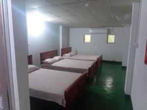 a room with four beds and a green floor at New Samanali Resort in Kataragama