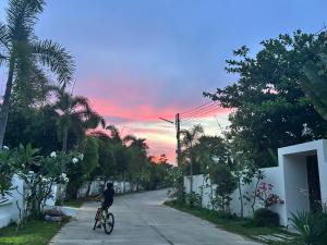 Eine Person, die bei Sonnenuntergang mit dem Fahrrad eine Straße entlangfährt in der Unterkunft cloud & countyard in Mae Rim