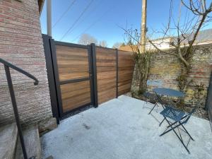 a fence with a gate and a table on a patio at Logement entier avec accès privé in Ambrines