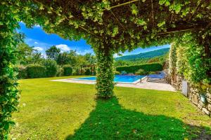 an ivy covered archway in a yard with a pool at Borgo di sotto, Il mulino in Cortona