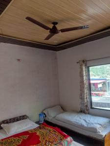 a room with two beds and a ceiling fan at Kanhaiya Hotel in Sonprayag