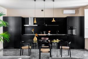 eine Küche mit schwarzen Schränken und einem schwarzen Tisch und Stühlen in der Unterkunft Palazzo Valguarnera - Suites & Luxury Apartments in Palermo