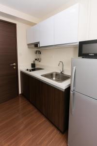a kitchen with a sink and a refrigerator at Velvet Vibe Chic Makati Stay Pool Gym 4034 in Manila