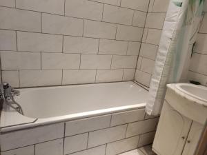 a white bathroom with a tub and a sink at Appartement avec terrasse 53m2 in Saint-Martin-de-Valamas