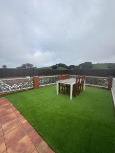 a white table and chairs on a patio with green grass at Casasturias in Candás +7 photos