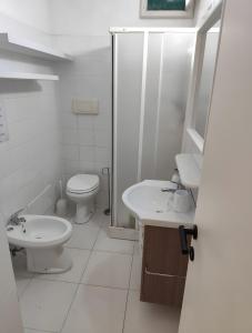 a white bathroom with a toilet and a sink at Villa il Caminetto in Geremeas