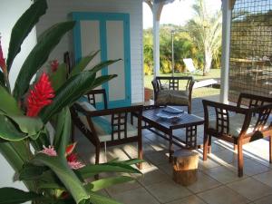 un porche con mesa, sillas y una planta en Belle Villa Créole, en Petit-Bourg