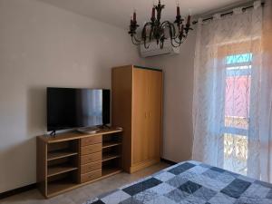 a bedroom with a flat screen tv and a dresser with a bed at Villa Topaz iun T4815 in Capoterra