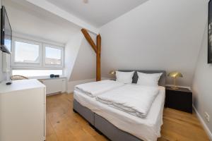 Ferienwohnung Strom ahoi - premium - modern - inkl Stellplatz - 200m zum Alten Strom - Wasserblick في فارنمونده: غرفة نوم بها سرير بملاءات بيضاء ونافذة