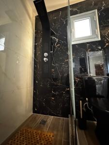 e bagno con doccia e parete in marmo nero. di Giannis Philoxenia a Paloúkia Altre 9 foto