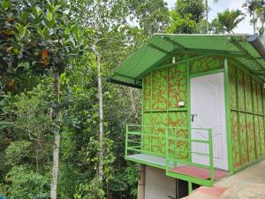 a green and white building with a door and trees at Bamboo leaf Homestay in Meppādi