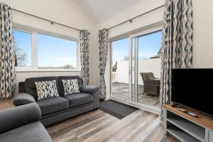 a living room with a couch and a flat screen tv at Fern Cottage - Dog Friendly Cottage with Hot Tub in Begelly