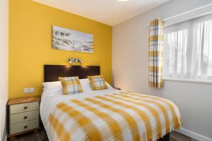 a bedroom with a bed with yellow walls and a window at Bramble Cottage - Dog Friendly Cottage Hot Tub in Begelly