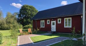 a red house with two chairs in front of it at Gårdshuset Orrefors in Orrefors