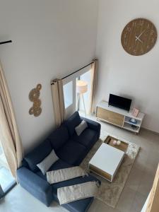 a living room with a blue couch and a clock at Appartement proche du lac de Vouglans in Charchilla