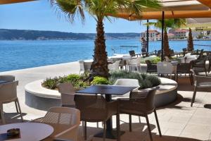 a restaurant with tables and chairs next to the water at Stone House Kaštela in Kaštela